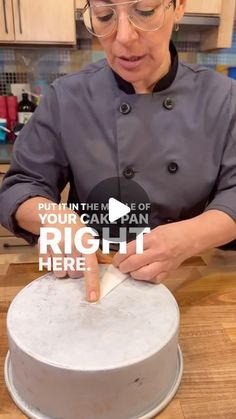 a woman in a chef's coat is decorating a cake with white frosting