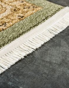 an area rug with various colors and fringes on the floor, closeup view