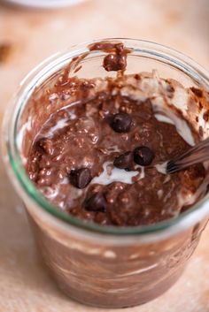 a glass jar filled with chocolate pudding and ice cream on top of a wooden table