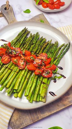 asparagus and tomatoes on a white plate