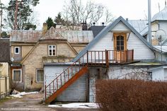 an old run down building with a staircase going up to the second floor and another house in the background