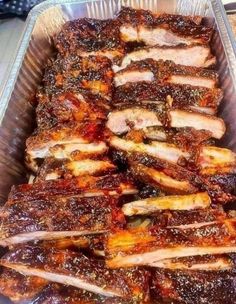 barbecue ribs in tin foil lined up on a counter top, ready to be cooked