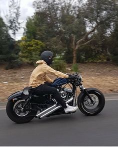 a man riding on the back of a black motorcycle down a curvy road