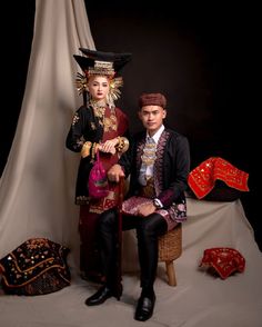 two people dressed in costume sitting on a chair together, posing for the camera with their arms around each other