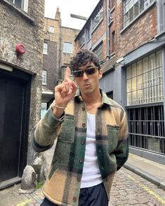 a man standing in the middle of an alley way pointing at something with his finger