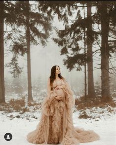 a woman standing in the snow wearing a long dress