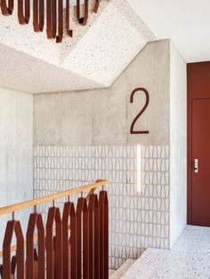 the number two is on the wall next to an iron railing and wooden handrail