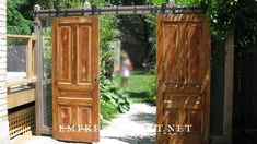 two wooden doors open in front of a garden