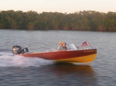 two people in a motorboat on the water with trees in the backgroud