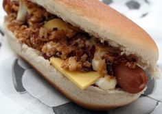 a close up of a hot dog on a bun with cheese and meat in it