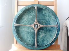 a large blue plate sitting on top of a wooden stand next to a white wall