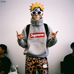 a man wearing a supreme hoodie and pants with his hands up in the air