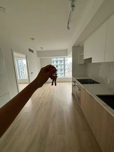 a person is holding a stuffed animal in an empty room with white walls and wood flooring