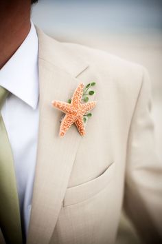 a man wearing a white suit with a starfish brooch on it's lapel