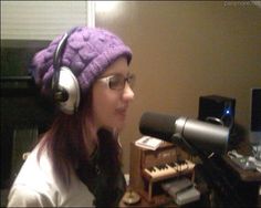 a woman wearing headphones sitting in front of a microphone and recording equipment on a desk