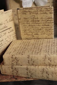 three old books are stacked on top of each other, with handwritten writing on them