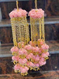 pink roses and gold beads hanging from a chandelier in front of some steps