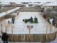 an outdoor ice rink with people standing around and playing hockey on it in the snow