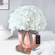 a pink vase with white flowers and a black ribbon