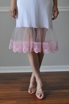 "Light Pink Lace/Tulle Lace Ruffle Trim - Slip Extender. An exquisite accessory for your wardrobe, this feminine slip worn with your skirt or dress will make you feel very special ! It is made of white nylon with elastic waistband and 9\" inches pink lace/tulle ruffle and trimmed with pink lace 4\" or your choice of color. Choose from 9 colors of tulle and lace. Standard length is - 25\" and petite is 21\". Available in color: #1-Red #2-White #3-Brown #4-Cream/Ivory #5-Fuchsia #6- Black #7- Ligh Fitted Ruffles Petticoat Balletcore Style, Fitted Ruffled Petticoat For Summer, Fitted Summer Petticoat With Ruffles, Summer Fitted Petticoat With Ruffle Hem, Fitted Pink Bottoms With Lace Trim, Spring Pink Stretch Petticoat, Feminine Fitted Summer Petticoat, Spring Balletcore Fitted Petticoat, Spring Fitted Ruffle Petticoat