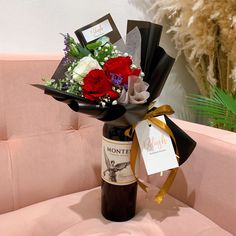 a bouquet of flowers sitting on top of a pink couch next to a bottle of wine