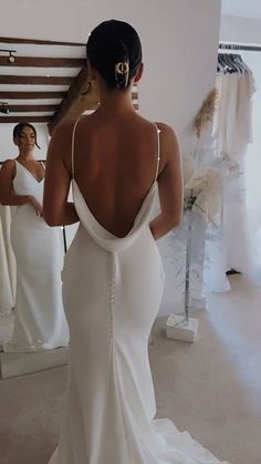 a woman in a wedding dress looking at herself in the mirror