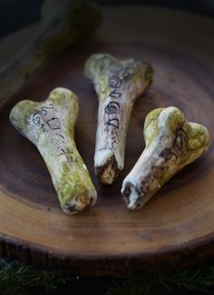 three dog bones with writing on them sitting on a wooden plate