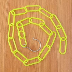 a yellow chain with a hook attached to it on a wooden surface next to a pair of scissors