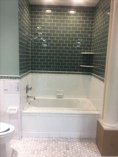 a bathroom with green and white tiles on the walls, floor, and bathtub