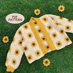 a crocheted sweater with sunflowers on it laying in the grass next to a sign that says pdf pattern