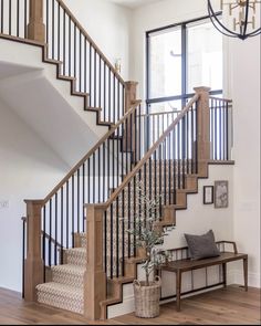 the stairs in this home are made of wood and wrought iron railings, along with a bench for seating