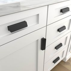 a white cabinet with black handles and knobs