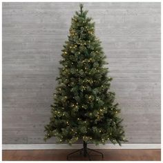 a small christmas tree with lights on it in front of a wooden wall and floor