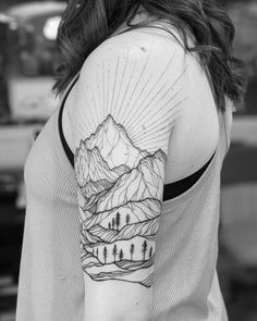 a woman's arm with mountains and trees tattoo on the left side of her arm