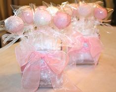 pink and white candies in clear glass vases with bows on the top, sitting on a table