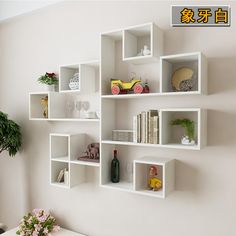 a white shelf with books, vases and other items on it next to a wall