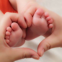 a close up of a person holding a baby's foot with both hands on it