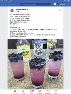 three glasses filled with blueberry vodka on top of a counter next to an empty bottle