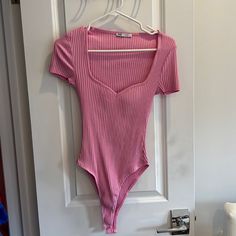 a pink bodysuit hanging on a white door