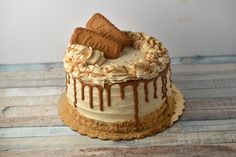 there is a cake with icing and chocolate on the top, sitting on a wooden table