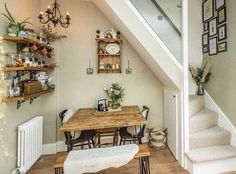 a table and some chairs in a room with stairs leading up to the second floor