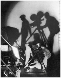 black and white photograph of people casting shadows on the wall