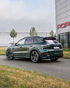 a green porsche cayen is parked on the side of the road in front of a building