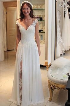 a woman standing in front of a mirror wearing a white dress with lace on it