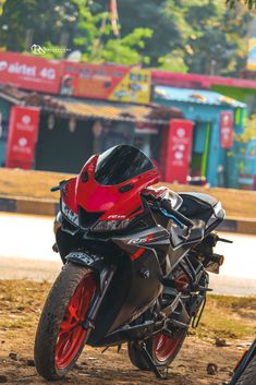 a red and black motorcycle parked on the side of a road next to a tree