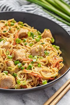 a bowl filled with noodles and meat on top of a table next to chopsticks