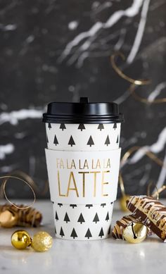 a coffee cup sitting on top of a counter next to some gold foiled decorations