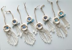 six evil eye macbook charms with tassels hanging from the strings on a white surface