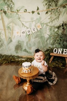 a baby sitting on the floor next to a cake