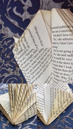 an origami book folded in half on top of a blue tablecloth with silver and white designs